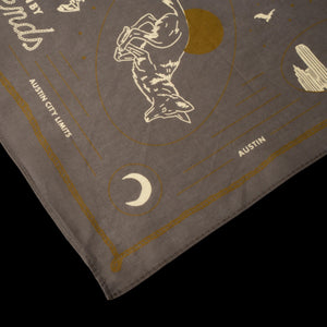 Gray bandana with gold and white designs and text on a black background
